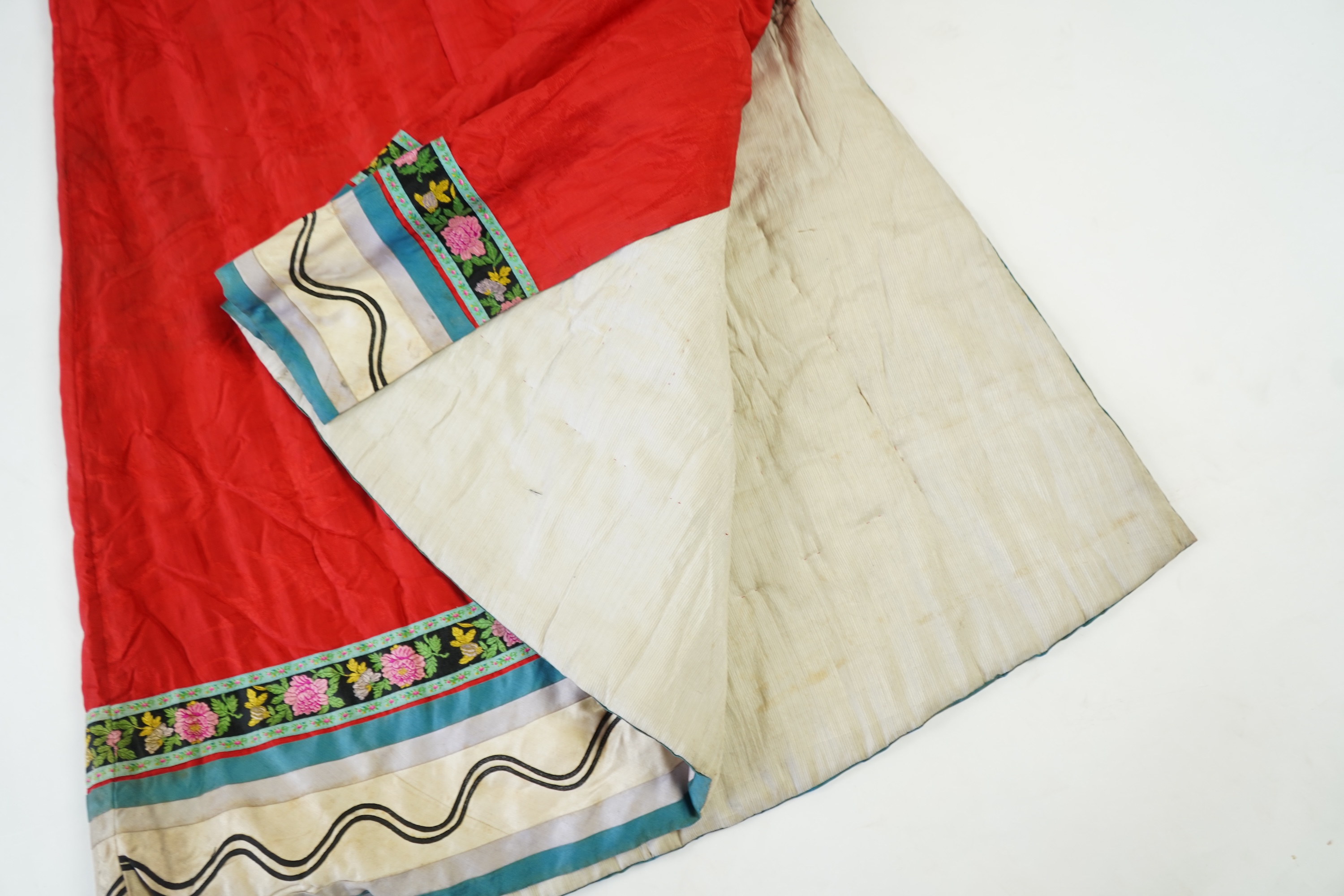 A late 19th century early 20th century Chinese red silk damask quilted Mandarin robe. Decorated with colourful rows braiding and ornate toggling. 116cm long. Condition - minor marks in places, may benefit from specialist